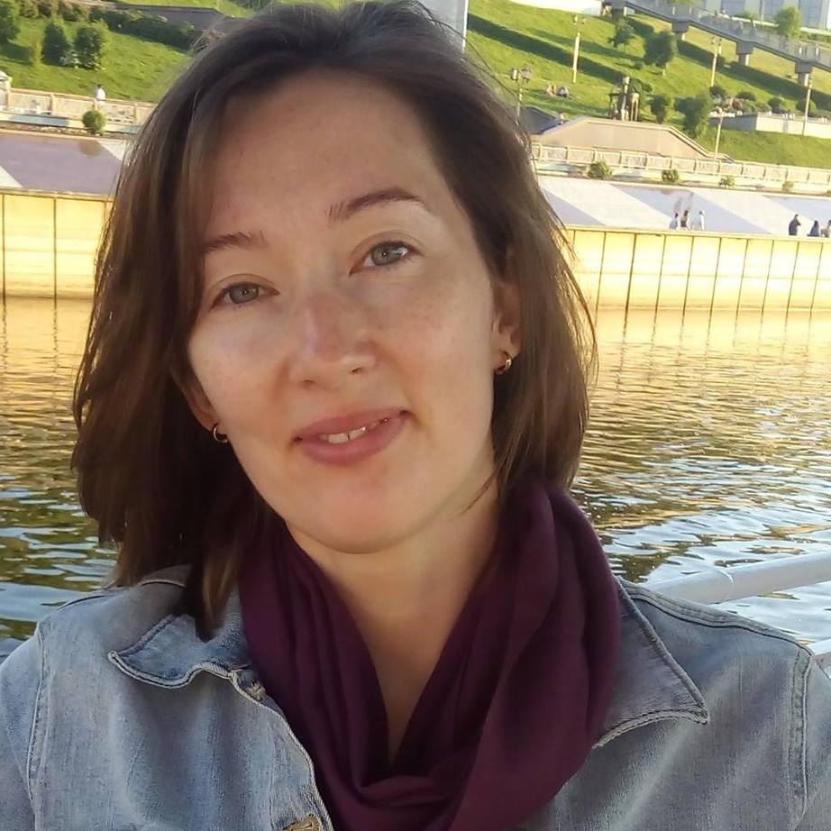 Head-and-shoulders image of a woman with fair skin and chin-length brown hair with a river and park in the background